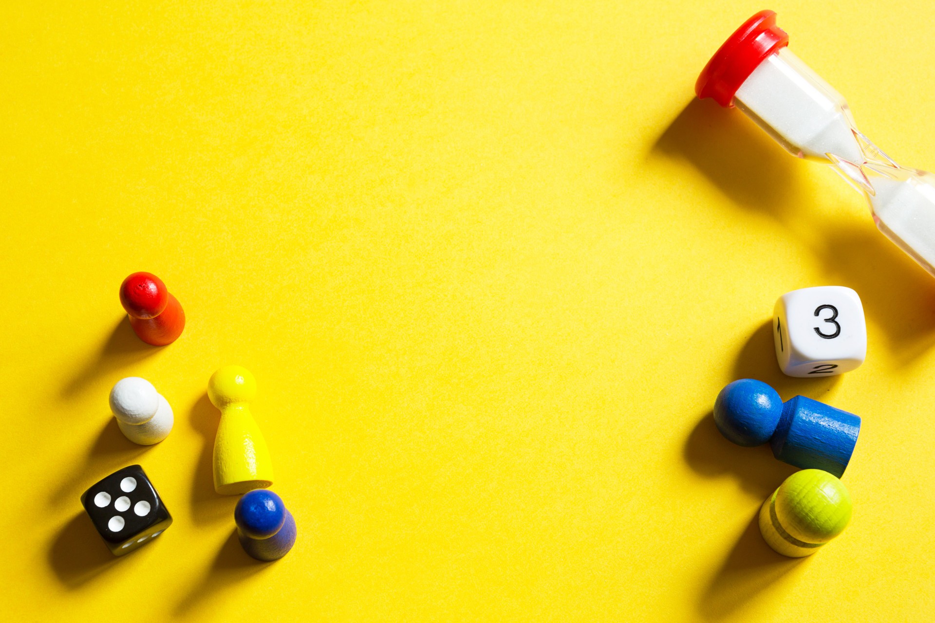 Layout of board games on a yellow background: dice, chips, hourglass timer. Entertainment at home for children and adults. Copy space Layout of board games on a yellow background: dice, chips, hourglass timer. Entertainment at home for children and adults. Copy space
